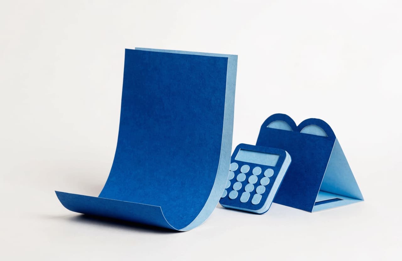 Paper-craft illustration of a curling letterhead page beside a paper calculator and a folded sign